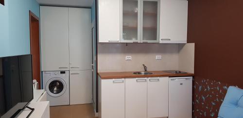 a kitchen with white cabinets and a washing machine at Апартамент Парк Несебър in Nesebar