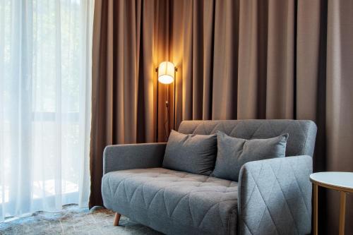 a living room with a couch and a lamp at RIVER Hotel & SPA in Călimăneşti