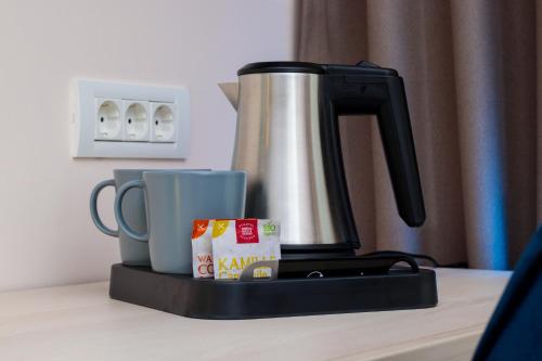 a coffee maker and two cups on a table at RIVER Hotel & SPA in Călimăneşti