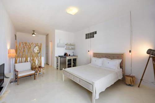 a white bedroom with a bed and a kitchen at Aigeis-milos in Agia Kiriaki Beach