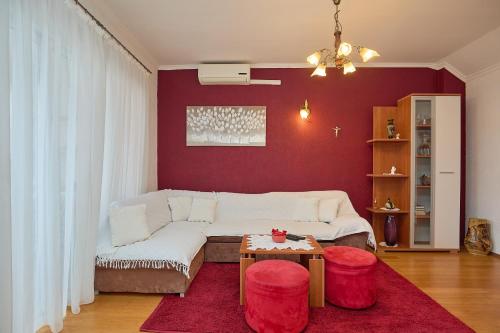 sala de estar con sofá blanco y pared roja en Agriculture & Holiday house Lasko, en Goveđari