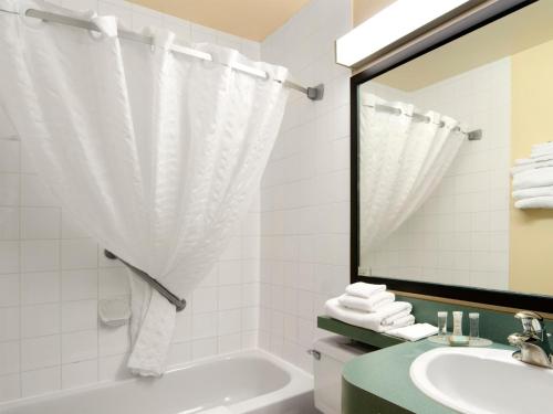 uma casa de banho com uma banheira, um lavatório e um espelho. em Travelodge by Wyndham Drumheller AB em Drumheller