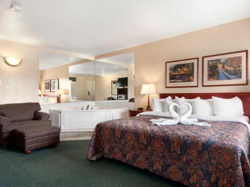 a hotel room with a bed and a bath tub at Travelodge by Wyndham Drumheller AB in Drumheller