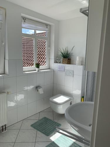 a white bathroom with a toilet and a sink at Ferienwohnung Mühlendamm in Bergen