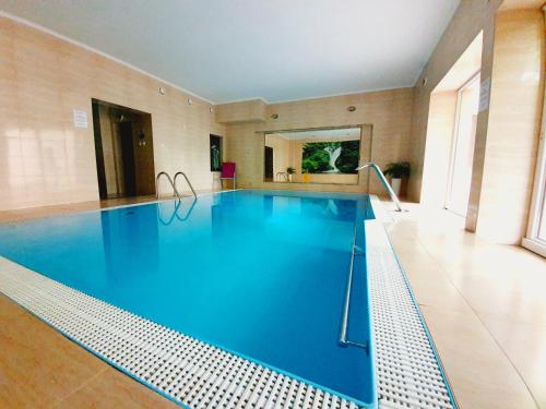 a large swimming pool with blue water in a building at Sadyba SPA in Karpacz