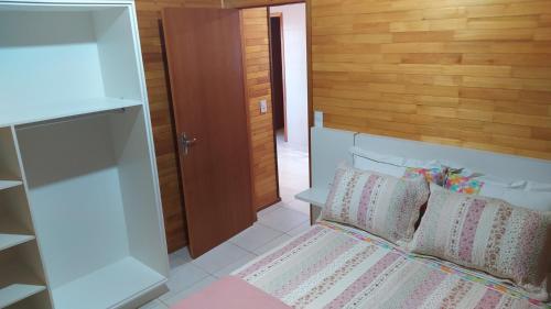 1 dormitorio con 1 cama y pared de madera en Apartamento Serrano 2 en São Joaquim