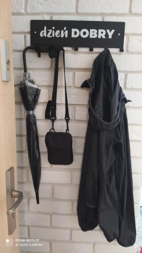 a black bag and umbrellas hanging on a wall at Apartament dla Dwojga - Apartament typu studio in Dziwnówek