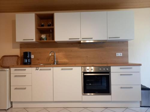 a kitchen with white cabinets and a sink and an oven at Ferienwohnung Tremmbach in Salzwoog