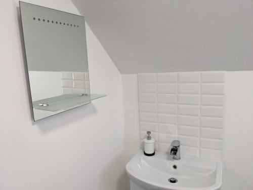 a white bathroom with a mirror and a sink at Central Apartment Newcastle in Newcastle