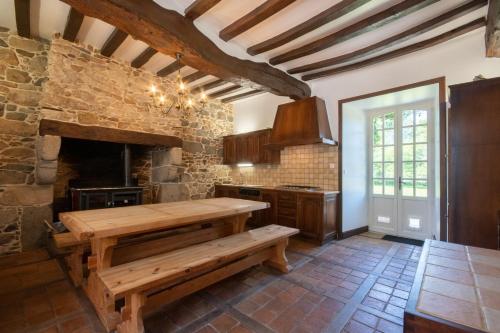 - une cuisine avec une table en bois et un mur en pierre dans l'établissement Manoir le Cosquer, à Pommerit-le-Vicomte