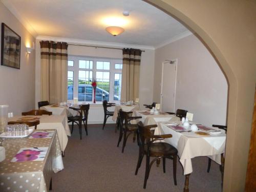 a dining room with white tables and chairs at The Ramblers in Trusthorpe