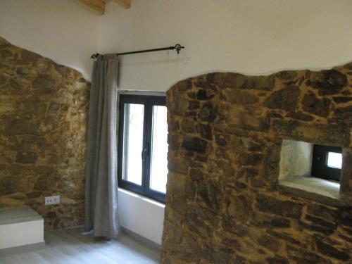Habitación con pared de piedra y ventana. en Casa Hozani, en Albarrol