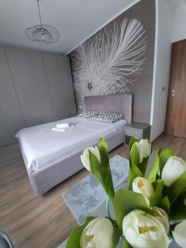 a bedroom with a bed and a table with flowers at Paula Apartment in Dumbrăviţa