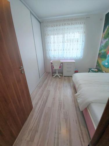 UisenteşにあるPaula Apartmentのベッドと机と窓のある寝室