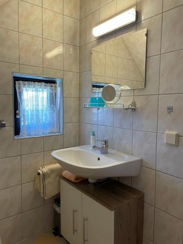Un baño con un lavabo blanco y un espejo. en Ferienwohnungen Rasinger, en Schiefling am See