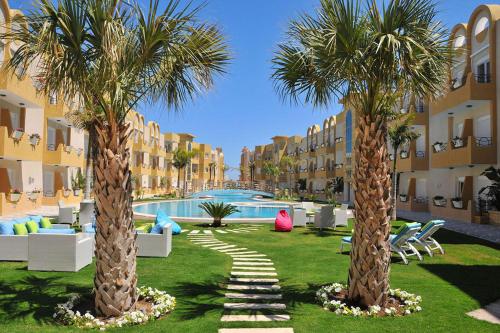 two palm trees in a yard in front of a building at Appartement S 1 résidence les Dunes sousse avec piscine in Sousse