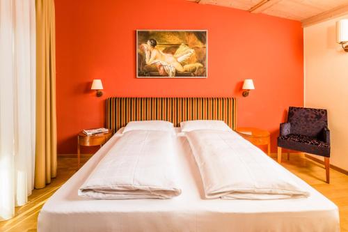 a large bed in a room with an orange wall at Hotel Traube in Bressanone