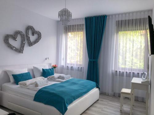 a bedroom with a bed with blue sheets and blue curtains at Gizell Apartment 1 in Sibiu