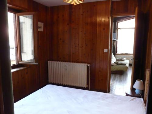 Schlafzimmer mit einem Bett sowie Holzwänden und -fenstern in der Unterkunft Appt 211 Taoures Copropriété SucBlanc in Molines-en-Queyras