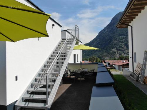 a balcony with stairs and tables and an umbrella at The AlpenHouse Gligic´s in Sautens