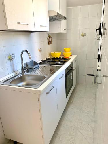 a white kitchen with a sink and a stove at ChiarAmare Vacanza, casa con Idromassaggio, vicino Maldive del Salento in Torre Pali 