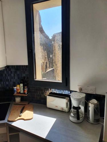 a kitchen counter with a view of a window at L'Exquishette de Lourmarin, un nid sur les toits. in Lourmarin