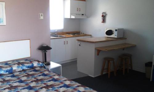a small kitchen with a bed and a microwave at Motel Royal in Cabano