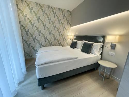 a bedroom with a large white bed and a table at Hotel Stella Alpina in Malcesine