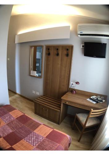 a room with a bed and a desk and a television at Hotel La Bussola in Padenghe sul Garda