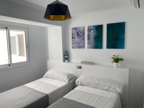 a bedroom with two beds and a window at PRECIOSO APARTAMENTO A ESTRENAR EN CENTRO DE NERJA in Nerja