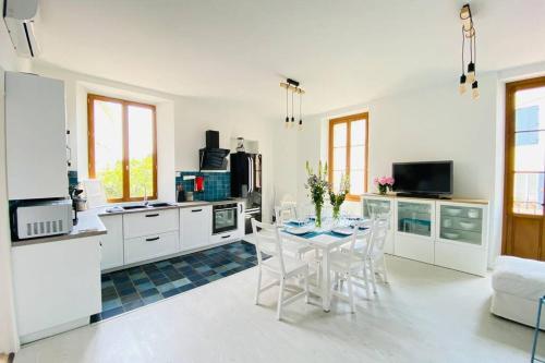 une cuisine avec des armoires blanches et une table et des chaises dans l'établissement Grand appartement proche plages & centre ville, à Cannes