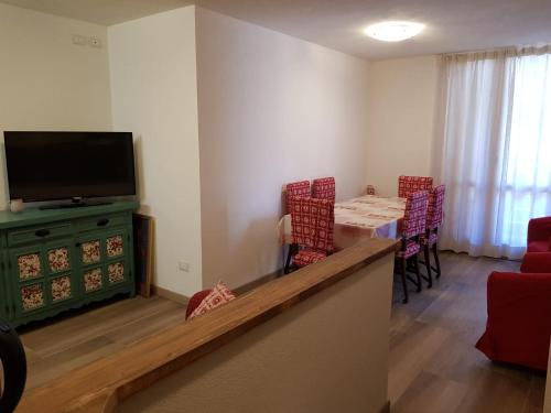 een woonkamer met een televisie en een tafel en stoelen bij Casa Sonia in Canazei