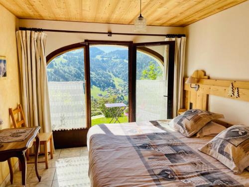 um quarto com uma cama e uma grande janela em Chambre d'Hôtes La Trace em La Clusaz