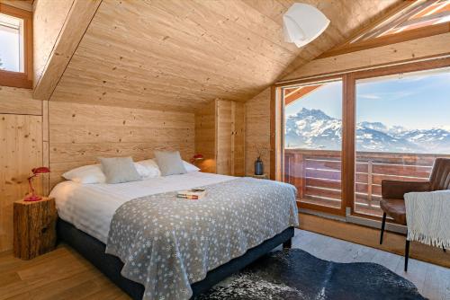 a bedroom with a bed and a large window at Les Mazots du Clos in Villars-sur-Ollon
