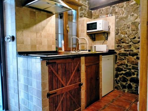 a kitchen with a wooden door and a sink at Casa con encanto in Aller
