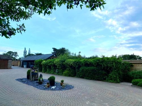 a garden with a brick walkway with potted plants at Amber Lodge Hickstead-C in Haywards Heath