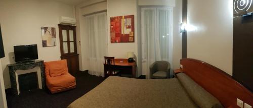 a living room with a couch and a chair and a television at Hotel de La Paix in Oloron-Sainte-Marie