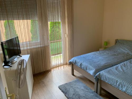 een slaapkamer met een bed, een tv en 2 ramen bij Alexa apartman in Hajdúszoboszló