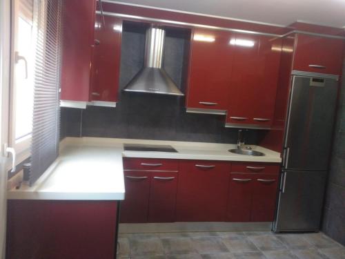 a kitchen with red cabinets and a stainless steel refrigerator at Casa Pimen in Gijón