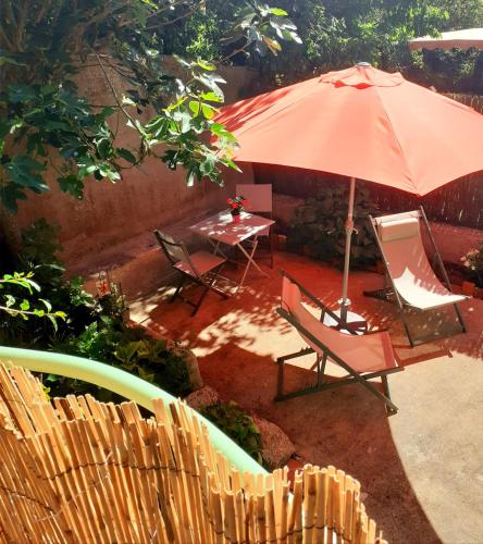 un patio con sombrilla, 2 sillas y una mesa en Studio 20mn Puy du fou et Hellfest, en Le Longeron