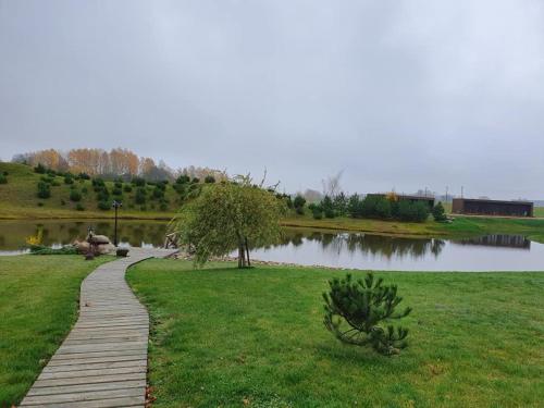 a wooden path through a park next to a lake at Stonkų sodyba Grapeldvaris in Varkaliai