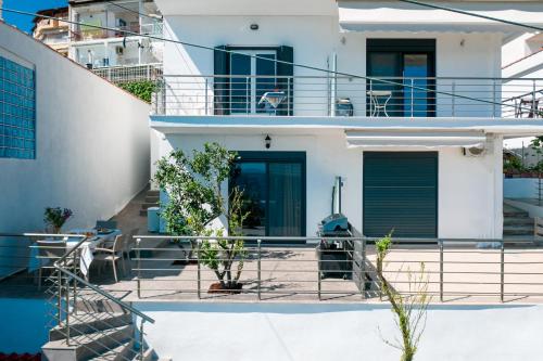 a white house with blue doors and stairs at Anemos Seaside Apartment in Neos Marmaras