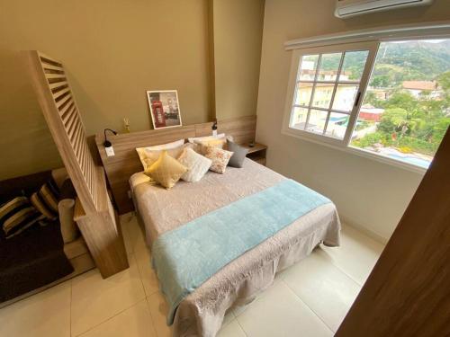ein Schlafzimmer mit einem Bett und einem großen Fenster in der Unterkunft Happy Flat Itaipava - Granja Brasil in Itaipava