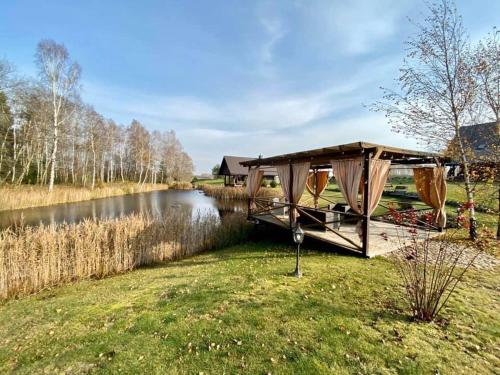 a boat with a canopy on the side of a river at Stonkų sodyba Grapeldvaris in Varkaliai