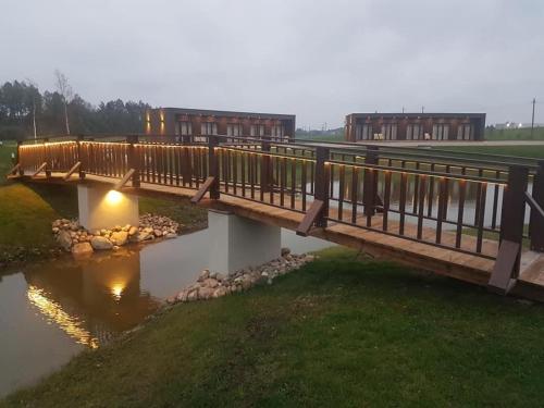 a bridge over a river with buildings in the background at Stonkų sodyba Grapeldvaris in Varkaliai