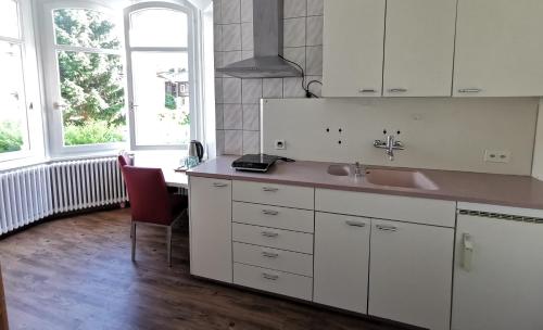 a kitchen with white cabinets and a sink and two windows at Interlaken Marco Hostel in Interlaken