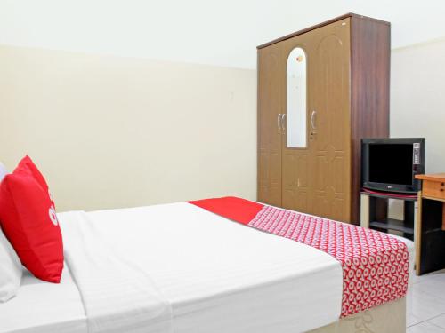 a bedroom with a bed with a red pillow and a tv at Capital O 90417 Hotel Batu Suli Internasional in Palangkaraya