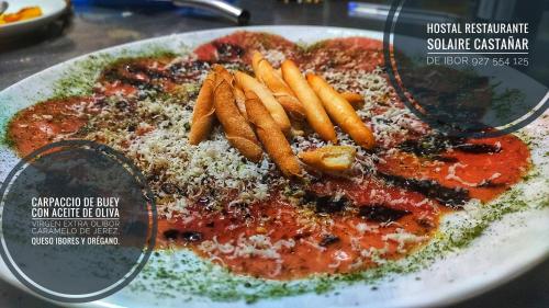 a plate of food with a pizza and french fries at Hostal Restaurante Solaire in Castañar de Ibor