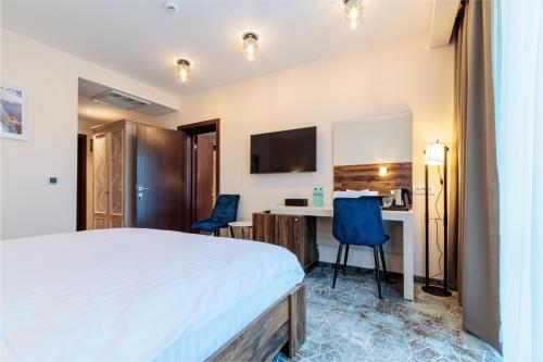 a hotel room with a bed and a desk and chairs at RIVER Hotel & SPA in Călimăneşti