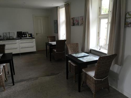 a dining room with tables and chairs and a kitchen at Safine B&B in Fåborg